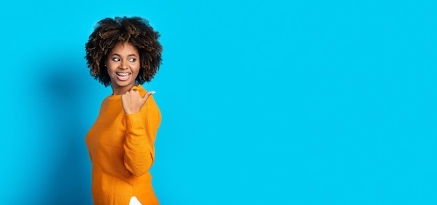 Excited black young woman showing empty space for ad