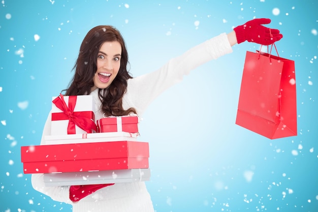 Excited brunette holding gifts and showing shopping bag against blue vignette