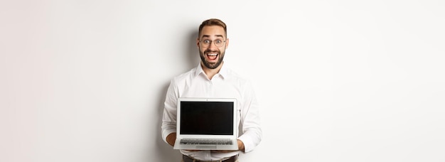 Excited businessman showing something on laptop screen standing happy over white background