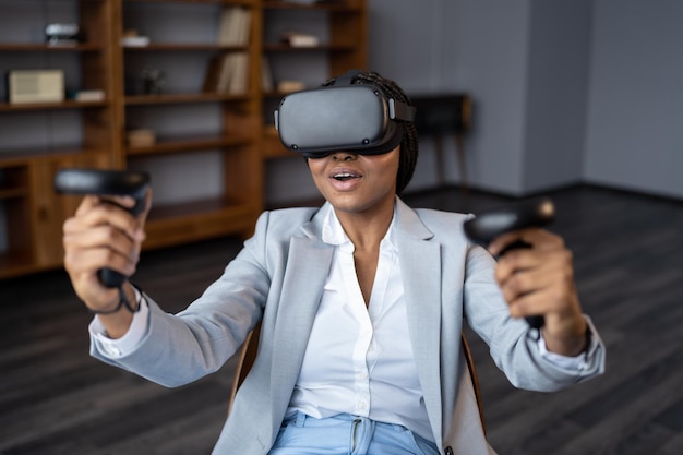 Excited businesswoman in virtual reality headset use joystick test vr goggles for gaming in office