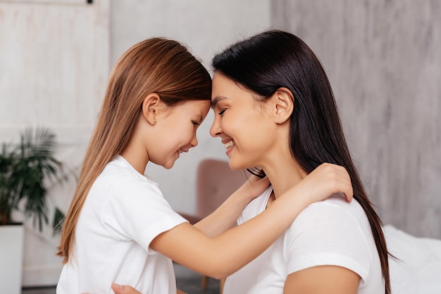 Excited child hugging her mother while standing closely face to face