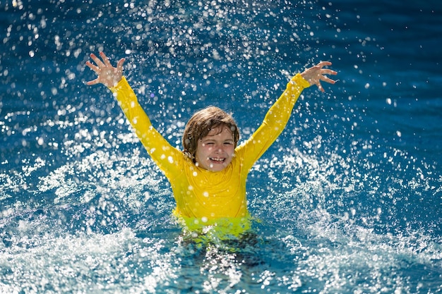 Excited child swimming little kid playing in blue water of swimming pool on a tropical resort at the