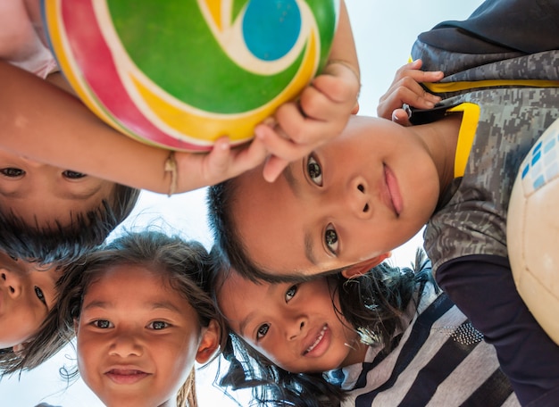 Excited children stand in circle hugging looking at camera at playing together