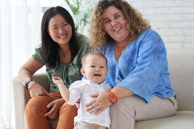 Excited curious little mixed-race boy with his two mothers spending weekend at home