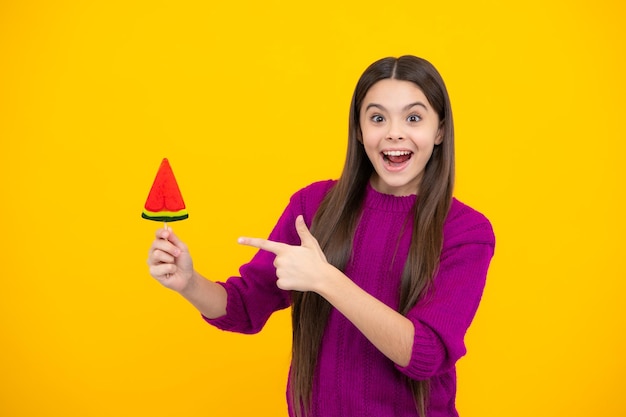 Excited face Funny child with lollipop over yellow isolated background Sweet childhood life Teen