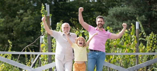 Excited family together with three different generations ages grandfather father and amazed son in spring garden