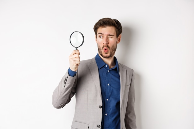 Excited funny guy in suit look through magnifying glass aside, checking out awesome thing