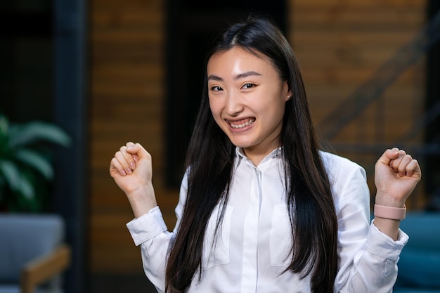 Excited funny young asian business woman celebrating success happy winner feeling overjoyed