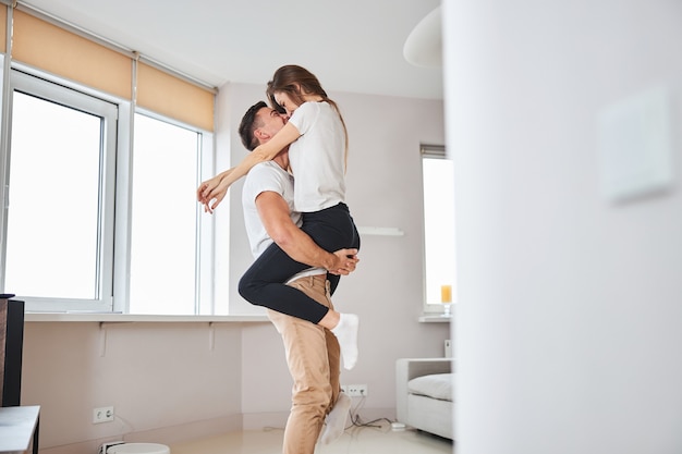 Excited gentleman and his girlfriend hugging at home