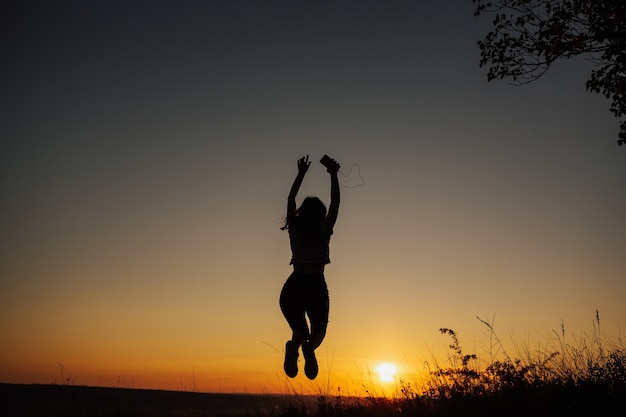 Excited girl jumping at sunset.