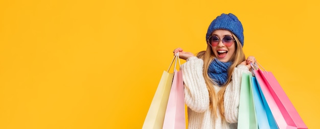 Excited girl in knitted hat and sunglasses with shopping bags