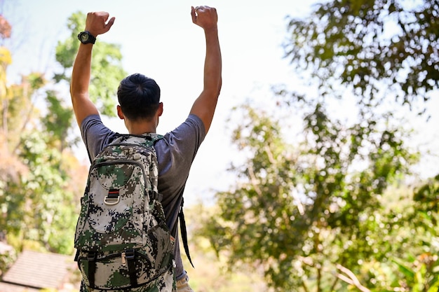 Excited and happy Asian male traveler hands up raising hands reaching at his destination