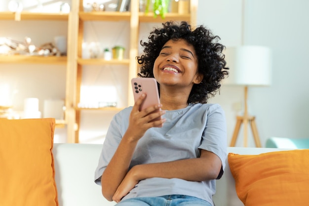 Excited happy young black african american woman holding cell phone laughing feeling joy getting mob