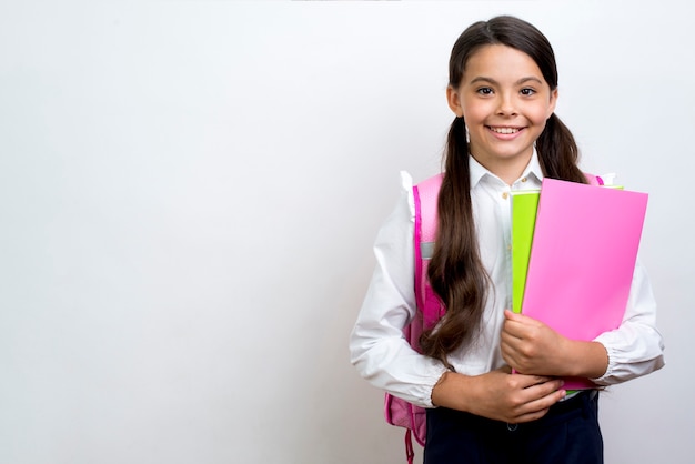 Excited Hispanic schoolgirl carrying copybooks