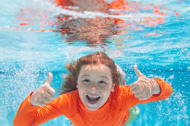 Excited kid boy with thumbs up swim and dive underwater kid with fun in pool under water Active healthy lifestyle water sport activity and swimming lessons on summer vacation with child