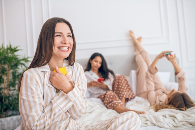 Excited. Long-haired cute girl holding a smartphone and looking excited