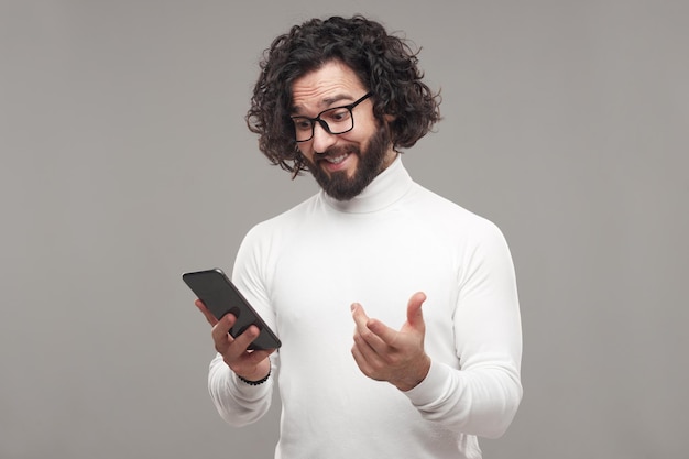 Excited man reading text message on smartphone in studio