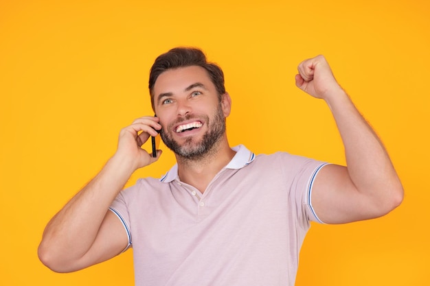 Excited man in tshirt using mobile phone isolated on studio background portrait of confidence middle