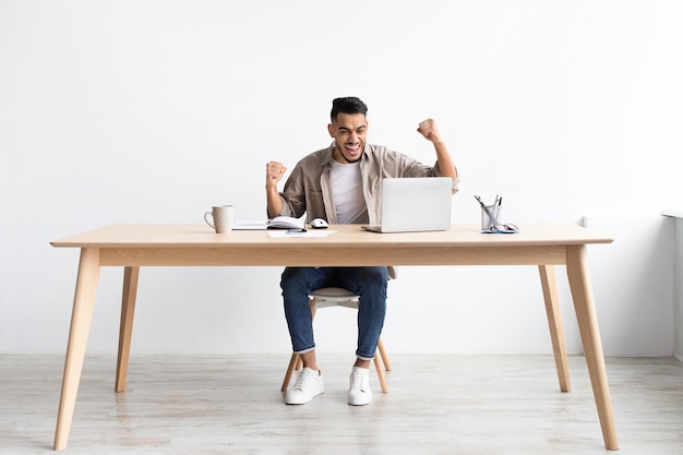 Excited man using pc celebrating success shaking fists screaming yes