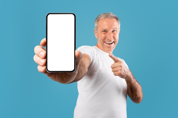 Excited mature man pointing finger at empty smartphone screen