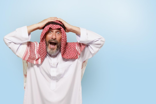 Excited middle eastern arabian man or muslim in traditional attire keffiyeh headscarf with smile