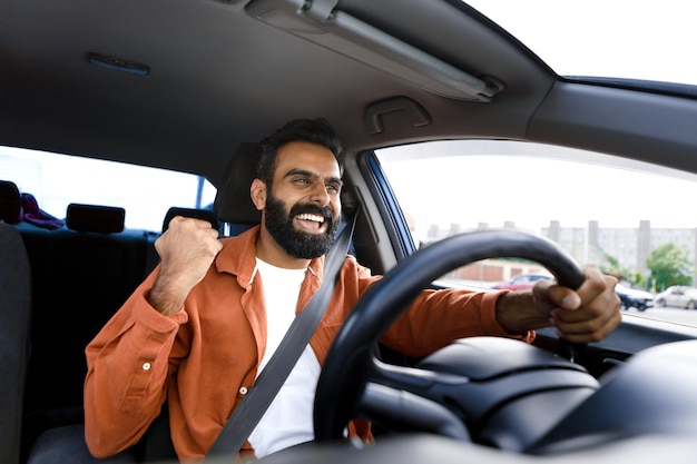 Excited middle eastern guy sitting in car gesturing yes