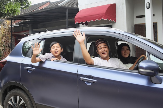 Excited muslim family are smiling and waving hand inside the car ready to go on holiday.