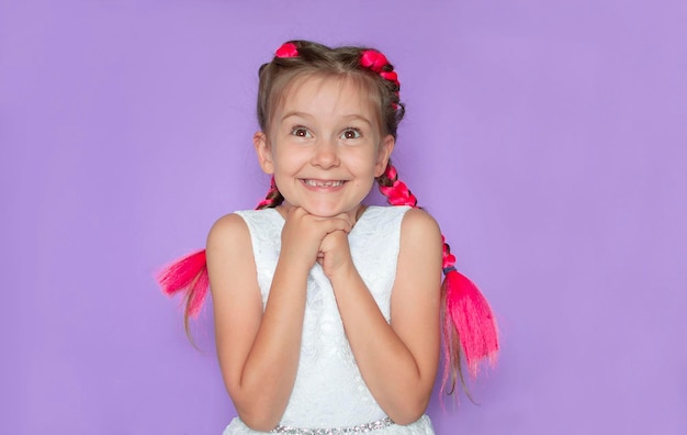 Excited overjoyed the girl feels happy looking at the camera on a purple background rejoicing in her success and victory clenching her fists with joy Positive emotions feelings