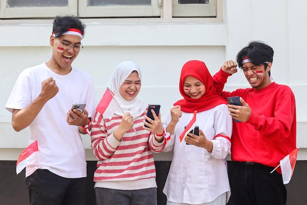 Excited people using mobile phone while holding Indonesian flag Indonesian independence day celebra