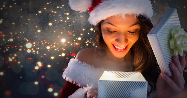 Excited Santa woman opening magical Christmas gift box with sparkling light