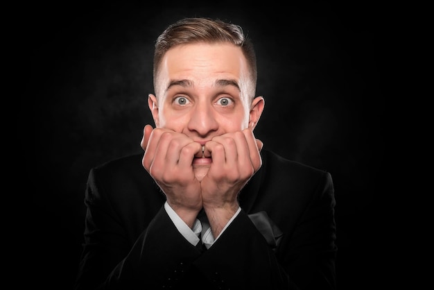 Excited or scared young man on a dark background.