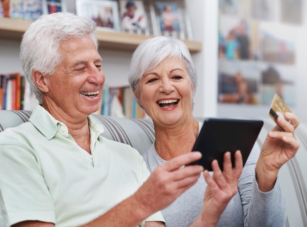 Excited senior couple tablet and credit card for online shopping on living room sofa together at home Happy elderly man and woman smiling on technology in ecommerce sale or payment on lounge couch