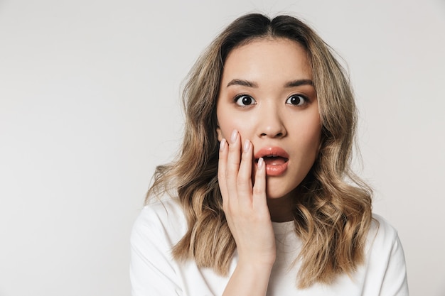 a excited shocked emotional cute young woman posing isolated over white wall wall