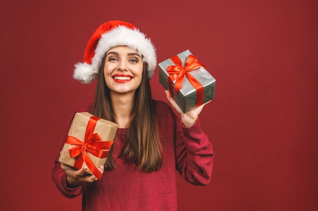 Excited surprised woman in red santa claus outfit holding present