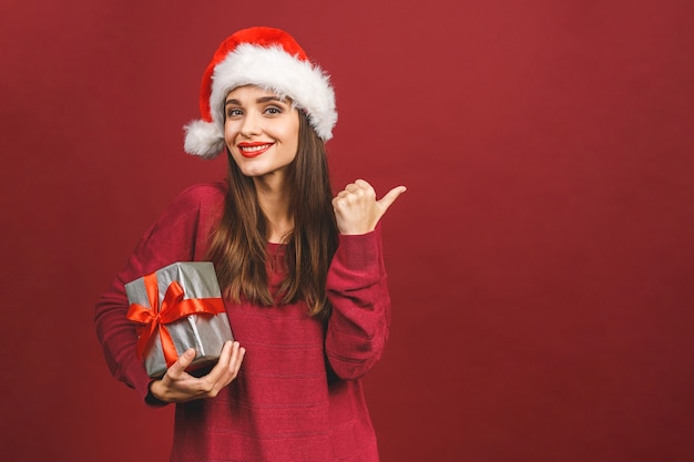 Excited surprised woman in red santa claus outfit holding present