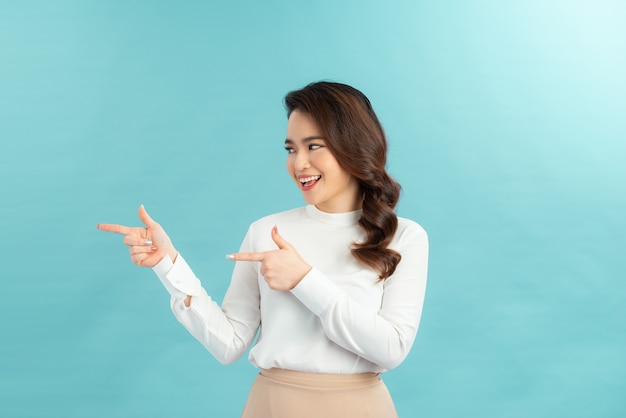 Excited and surprised young happy woman astonished pointing looking left side blank space for your promo, standing white background fascinated