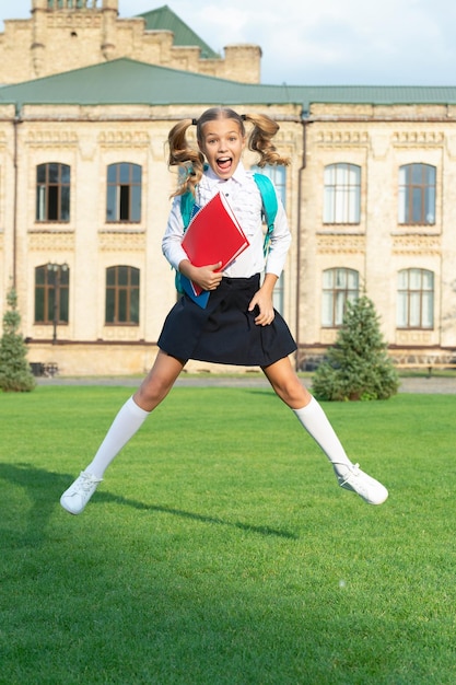 Excited teen girl in school uniform jumping midair Energetic teenage girl back to school