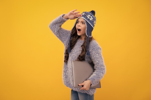 Excited teenager school girl Autumn school holiday Back to school Teenager schoolgirl in autumn clothes hold laptop on yellow isolated studio background