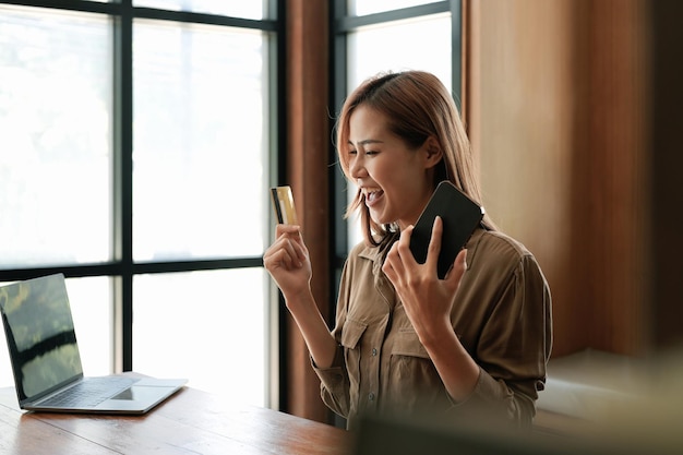 Excited woman holding credit card and using mobile phone online shopping black friday