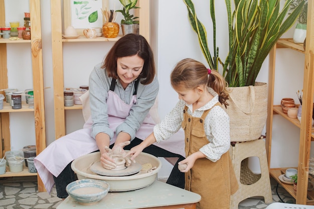 Excited woman shaping a clay case showing it to her daughter