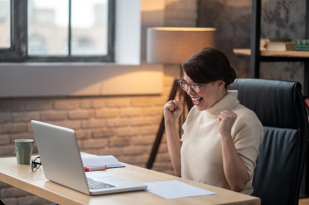 An excited woman sitting at the laptop and waiting for the updates