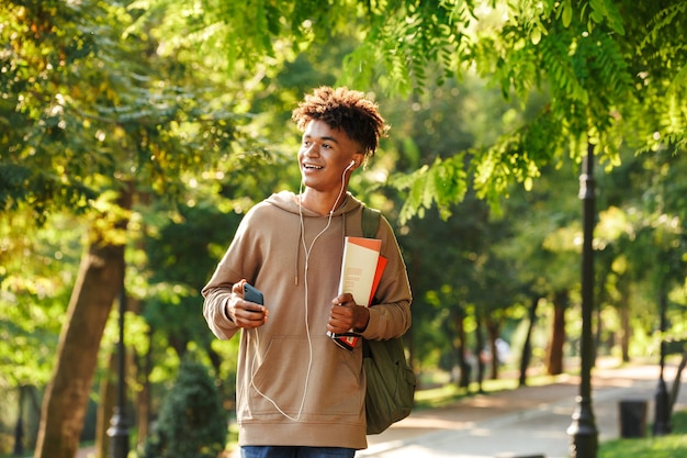 Excited young african guy with backpack walking