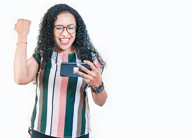 Excited young afro girl holding phone celebrating something Happy afro woman holding smartphone and celebrating isolated