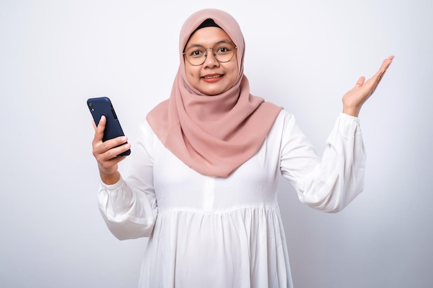 Excited young Asian Muslim woman using a mobile phone and celebrating success getting good news