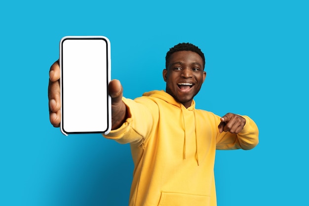 Excited young black guy showing smartphone with mockup