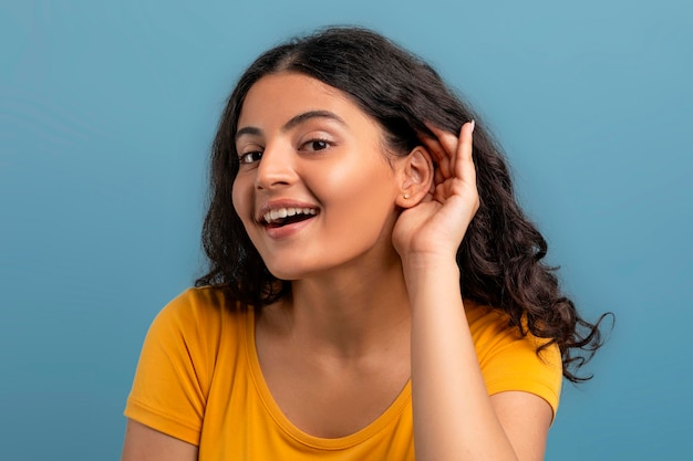 Excited young indian woman gesturing on blue background