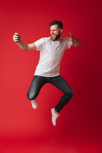 Excited young man make selfie by mobile phone jumping.