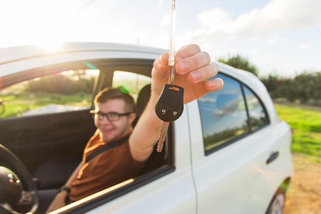 Excited young man showing a car key inside his new vehicle.