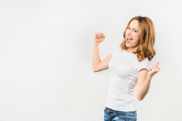 Excited young woman clenching her fist against white backdrop