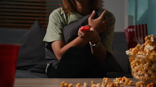 Excited young woman eating popcorn while enjoying in movie night at home